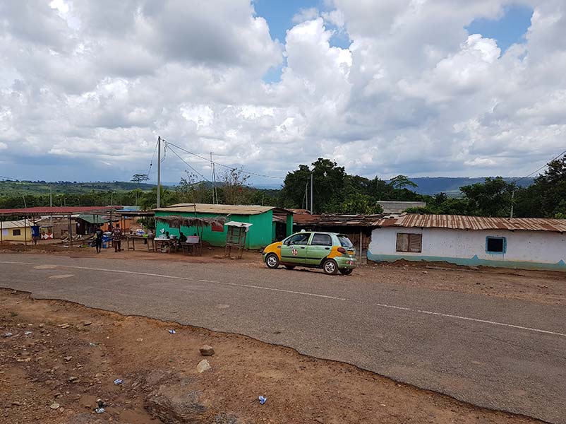 flat huts and a sales booth behind a small green and yellow car